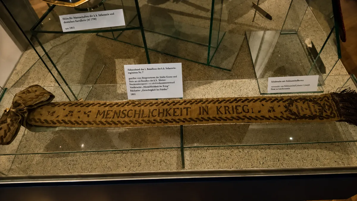 Historisches Fahnenband von 1801 mit der Stickerei „Menschlichkeit in Krieg“, ausgestellt im Heeresgeschichtlichen Museum Wien